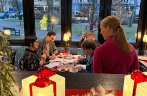 ihmisiä jouluisen pöydän ääressä