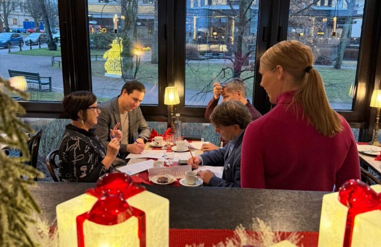 ihmisiä jouluisen pöydän ääressä