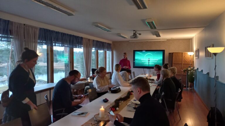 ryhmä pöydän ympärillä valmennustilaisuuden kick-offissa