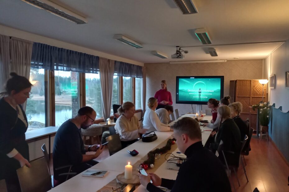 ryhmä pöydän ympärillä valmennustilaisuuden kick-offissa