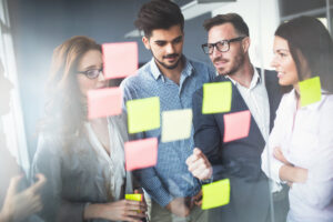 ihmiset ideoimassa yhdessä post-it lappujen edessä